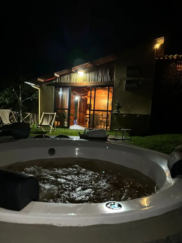 Hidromassagem acesa à noite em frente ao chalé iluminado